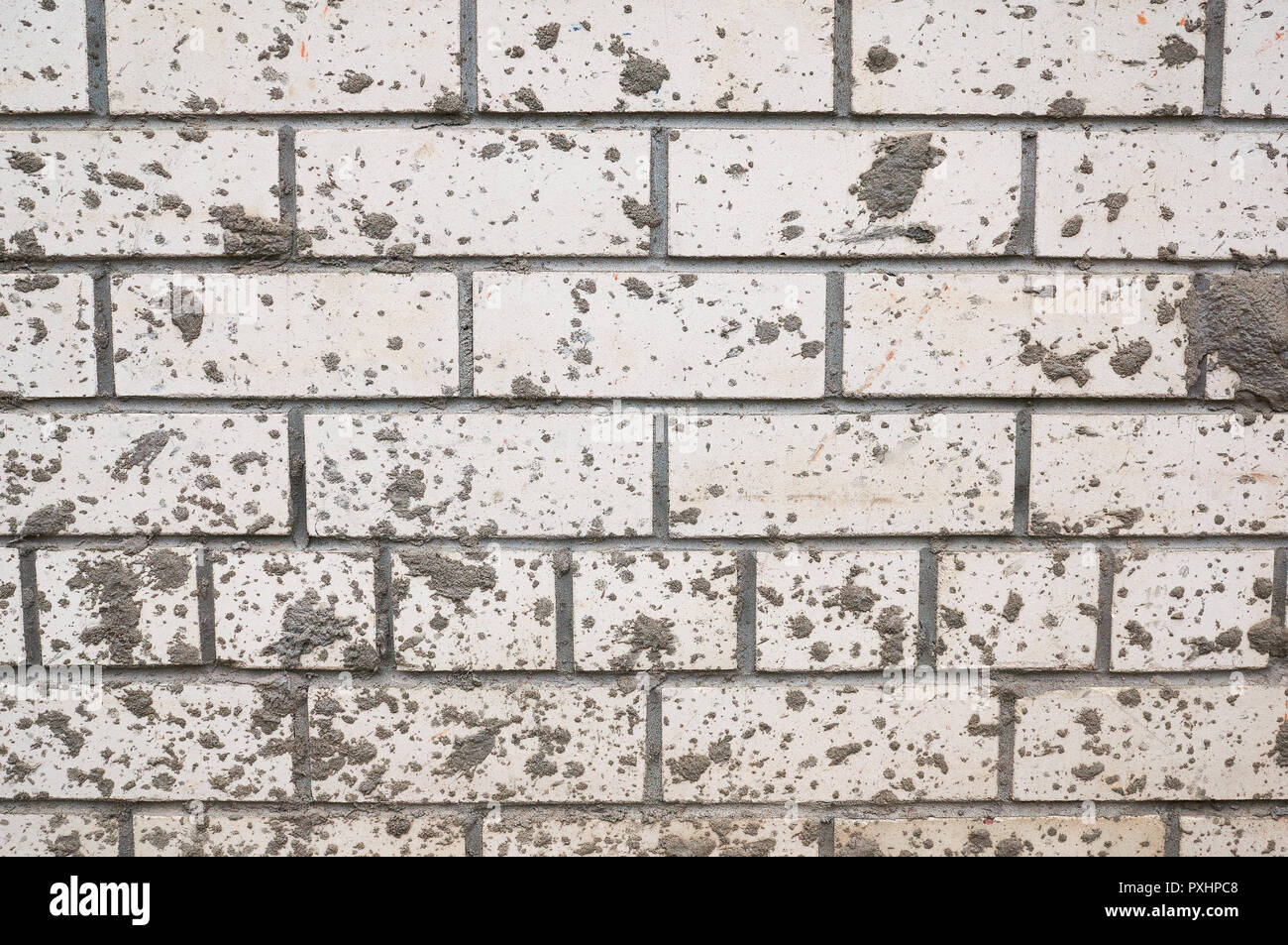 Muro di mattoni di colore bianco macchiato schizzi di fango. Foto Stock