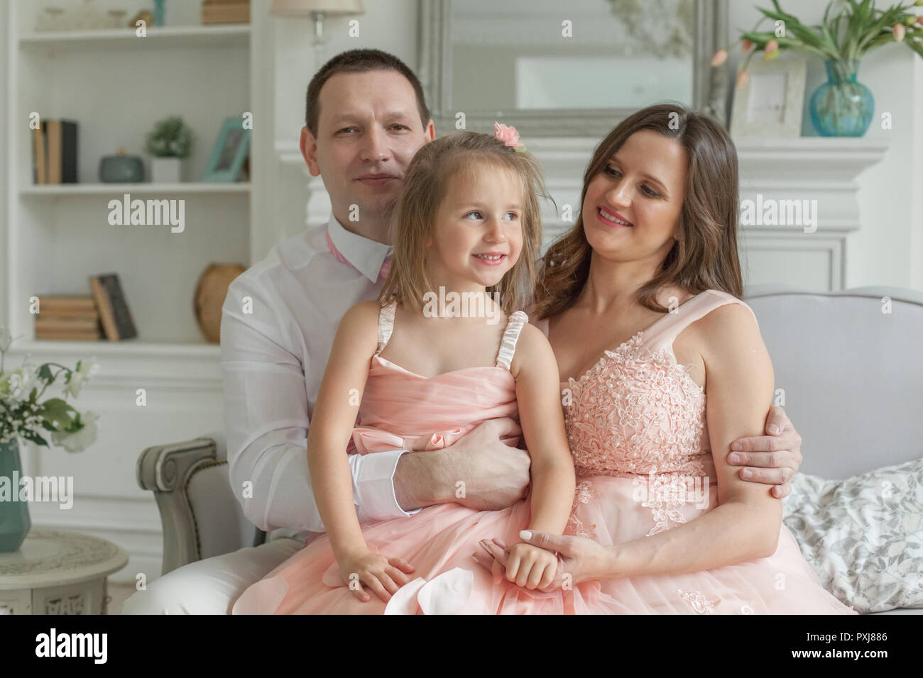 Ritratto di genitori felici con la bellissima figlia a casa. Famiglia deliziosa, espressioni positive. Affettuosa madre e padre con bambino Foto Stock