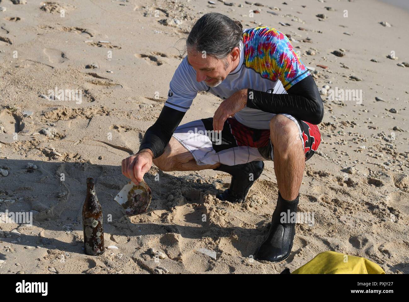 (181023) -- HAIKOU, Ott. 23, 2018 (Xinhua) -- Canadian Craig Anderson guarda una porcellana di rifiuti e una bottiglia ha prelevato durante una immersione in mare al largo della costa ovest Isola di Sanya, Cina del sud della provincia di Hainan, Sett. 20, 2018. Anderson è arrivato in febbraio presso il West isola abitata da circa 4 mila persone. La gente del posto considerato Anderson come scavenger quando egli per primo arrivato, come egli ha vagato intorno alla spiaggia quasi ogni giorno, il prelievo driftwood, bottiglie di plastica in frantumi bicchieri, e rusty pezzi di ferro. Col passare del tempo, la gente del posto si rese conto che Anderson è un artista che si dedica in env Foto Stock