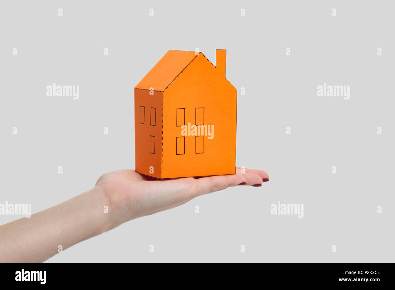 Donna Uomo mano azienda e mostra carta arancione modello di casa. piscina studio shot, isolata su uno sfondo grigio. Foto Stock