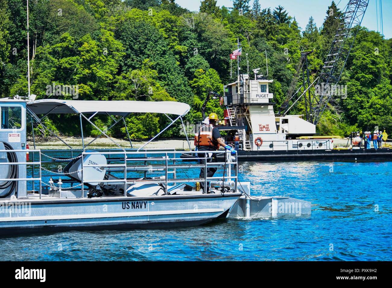 BLAKE ISLAND, nello Stato di Washington (06 giugno, 2017) una nave della Marina Militare esegue open water scrematura operazioni per recuperare il carburante da una simulazione di fuoriuscite di carburante, mentre M/V Puget distribuisce un braccio durante un braccio del giunto di distribuzione e Spill Response esercizio vicino a Blake Island, nello Stato di Washington Durante l'esercizio, i soccorritori dall esercito Corpo degli Ingegneri e la protezione di litorale XIII quartiere di risposta e Advisory Team distribuiti due sezioni del braccio di contenimento dalla M/V Puget per proteggere la linea di costa e di contenere il combustibile fuoriuscito. Foto Stock