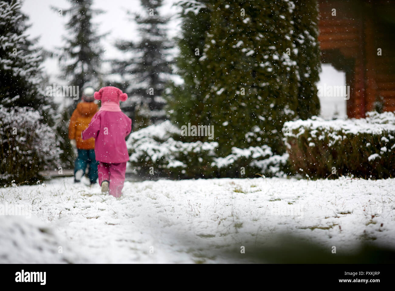 Due bambini stanno camminando lungo la strada innevata, vista posteriore Foto Stock