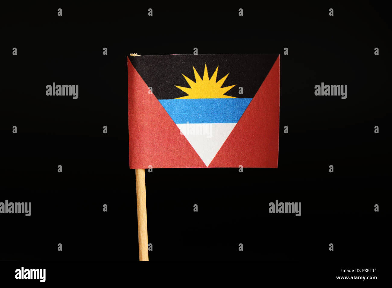 Una bandiera ufficiale di Antigua e Barbuda sul bastone di legno su sfondo nero. Stato situato in america centrale ed è stato insulare. Vi ha vissuto mai Foto Stock