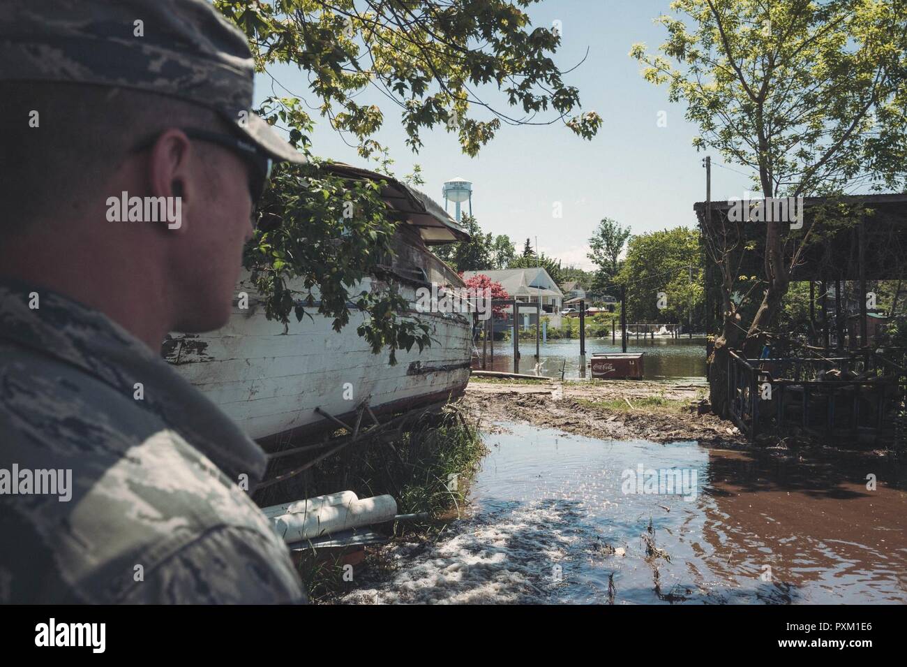 Il personale Sgt. James McCormick, un aviatore assegnato alla 107th gruppo medico, Niagara Falls riserva d'aria Stazione, New York Air National Guard, controlla il flusso di acqua che viene pompato da una casa locale, Olcott, N.Y., Giugno 8, 2017. Quando il pompaggio di acqua di case a causa delle inondazioni e dall aumento dei livelli delle acque nel lago Ontario, l'acqua deve essere pompato fuori in una zona dove non possa rifluire nella casa e a volte può essere nel cantiere di proprietari di abitazione. Foto Stock