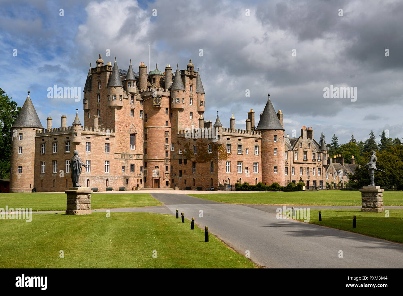 Prato anteriore di Glamis Castle casa d'infanzia di regina madre con le statue del Re Giacomo I e Carlo I con sole e nuvole Scotland Regno Unito Foto Stock