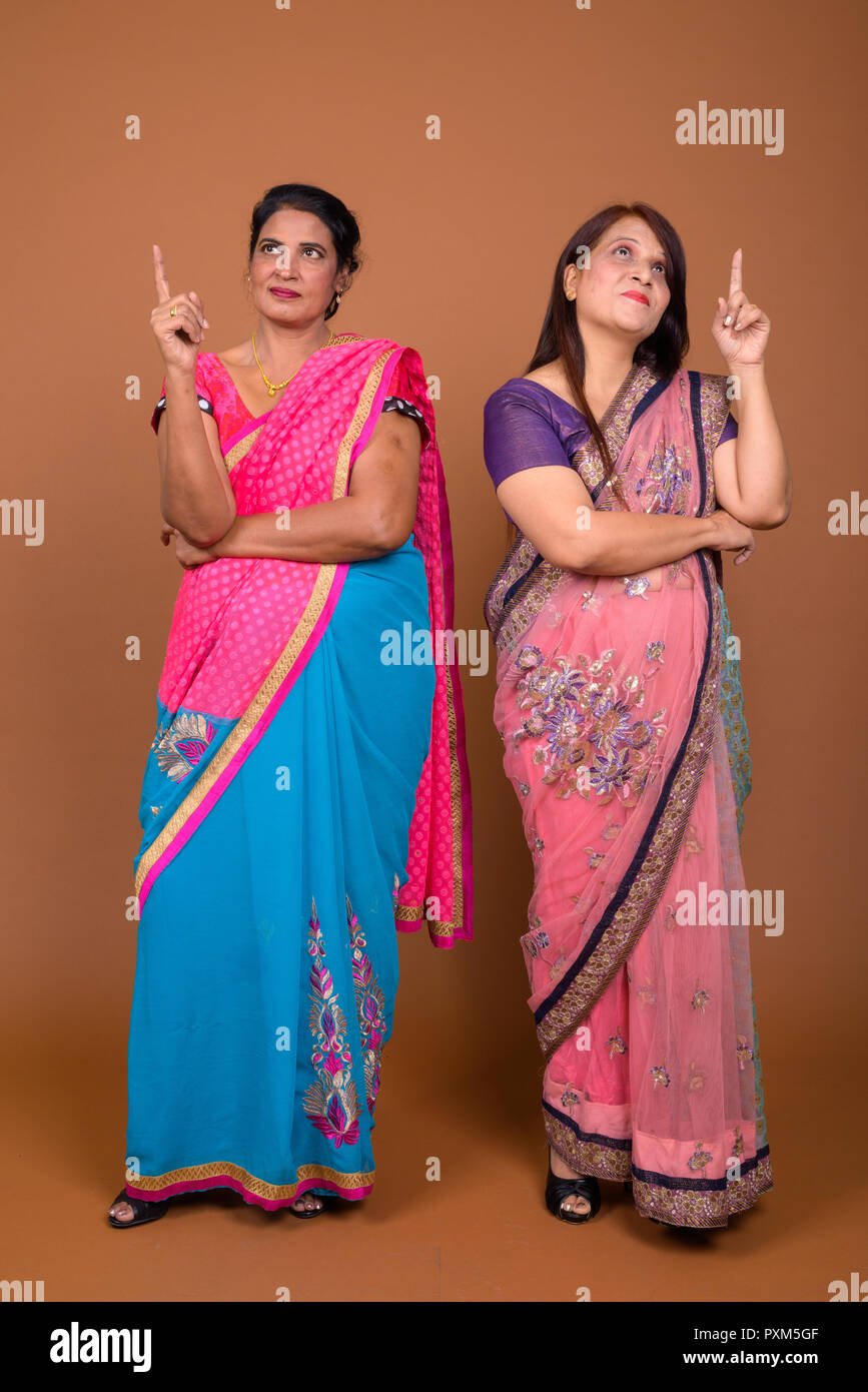 Due felice coppia donne indiane che indossa gli abiti tradizionali e puntare il dito fino Foto Stock