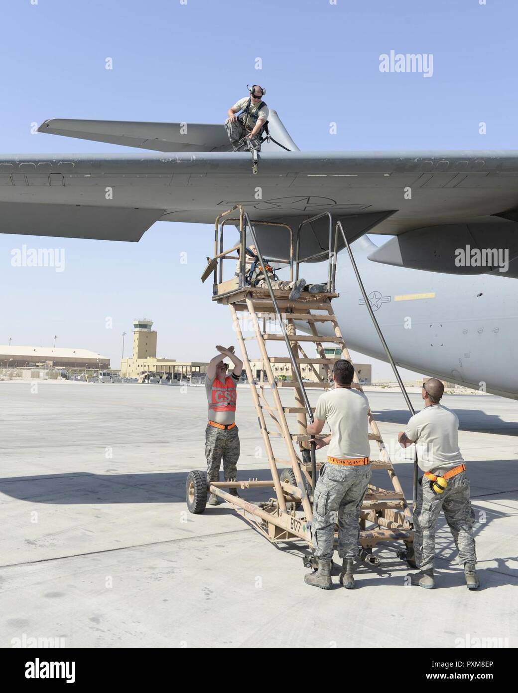 Stati Uniti Air Force Airman 1. Classe Giacobbe Trimble, orientamento e di controllo tecnico, guarda dall'ala di un C-17 Globemaster III come Senior Airman Kyle Sherburne, comunicazione e navigazione tecnico, giubbotto arancione, guida il personale Sgts. Brett Riso, capo equipaggio, a sinistra e a Gerardo Pesebre, Jr., di riparazione e di bonifica capo equipaggio, a destra mentre si spostano le scale di salvataggio in posizione durante una caduta esercitazione di protezione Al Udeid Air Base, Qatar, Giugno 6, 2017. Il dispositivo di protezione anticaduta esercizio è stata condotta dai membri del 8° Expeditionary aria squadrone di mobilità a sostegno della protezione anticaduta Mon di sensibilizzazione Foto Stock