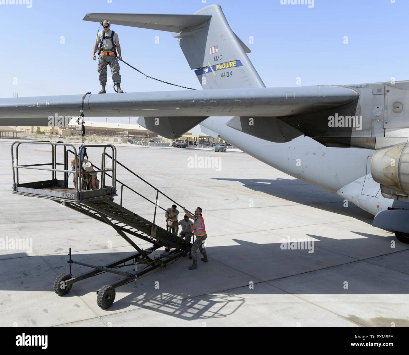 Stati Uniti Air Force Airman 1. Classe Giacobbe Trimble, orientamento e di controllo tecnico, guarda dall'ala di un C-17 Globemaster III come Sgts personale. Brett Riso, capo equipaggio, sinistra, Gerardo Pesebre, Jr., di riparazione e di bonifica capo equipaggio, centro e Senior Airman Kyle Sherburne, comunicazione e navigazione tecnico, destra, spostare il salvataggio scale in posizione durante una caduta esercitazione di protezione Al Udeid Air Base, Qatar, Giugno 6, 2017. Il dispositivo di protezione anticaduta esercizio è stata condotta dai membri del 8° Expeditionary Aria Mobilità Squadron, a sostegno della protezione anticaduta mese di sensibilizzazione ed è stata progettata Foto Stock