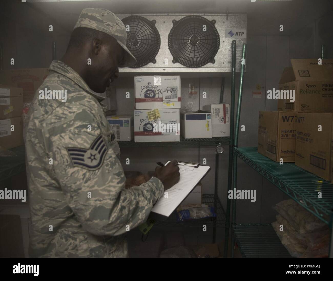 Stati Uniti Air Force Staff Sgt. Cornelius Bransah, l'NCO responsabili della sicurezza alimentare e igienico-sanitari assegnati al sesto Aerospace Medical Squadron, scrive note dopo l'ispezione di un congelatore ad entrata diretta a MacDill Air Force Base, Fla., 13 giugno 2017. Controlli Bransah date, come pure la temperatura del congelatore per garantire una corretta sicurezza alimentare. Foto Stock