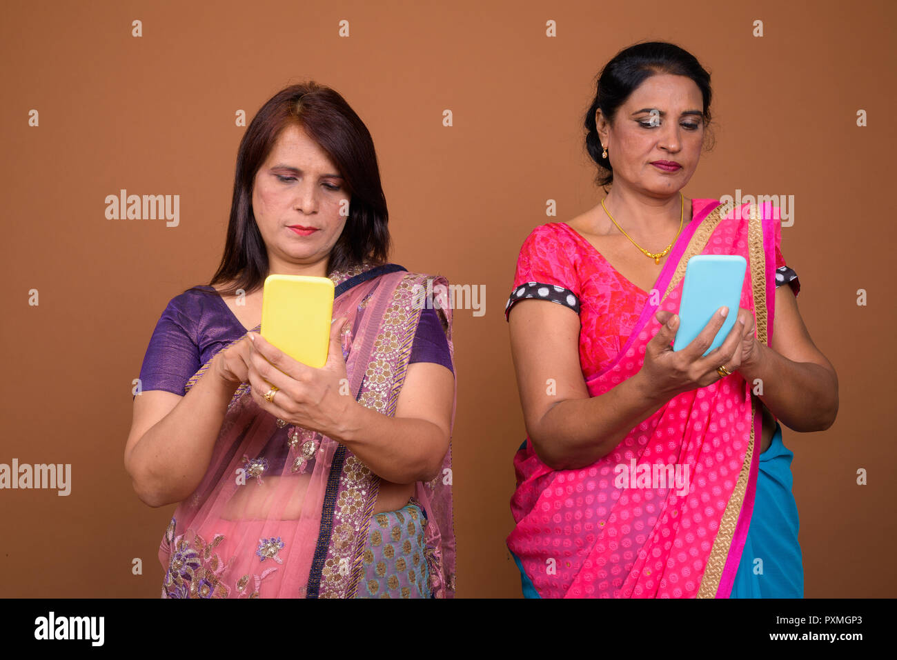 Due coppia donna indiana utilizzando il telefono cellulare Foto Stock