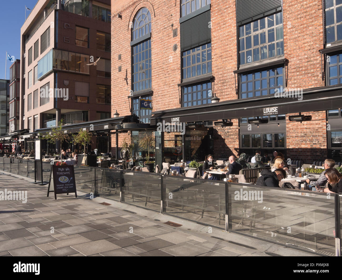 La Aker Brygge area nel centro di Oslo Norvegia ha molti ristoranti con vista del fiordo, posti a sedere esterni essenziali in un giorno di sole, qui !Louise ' Foto Stock