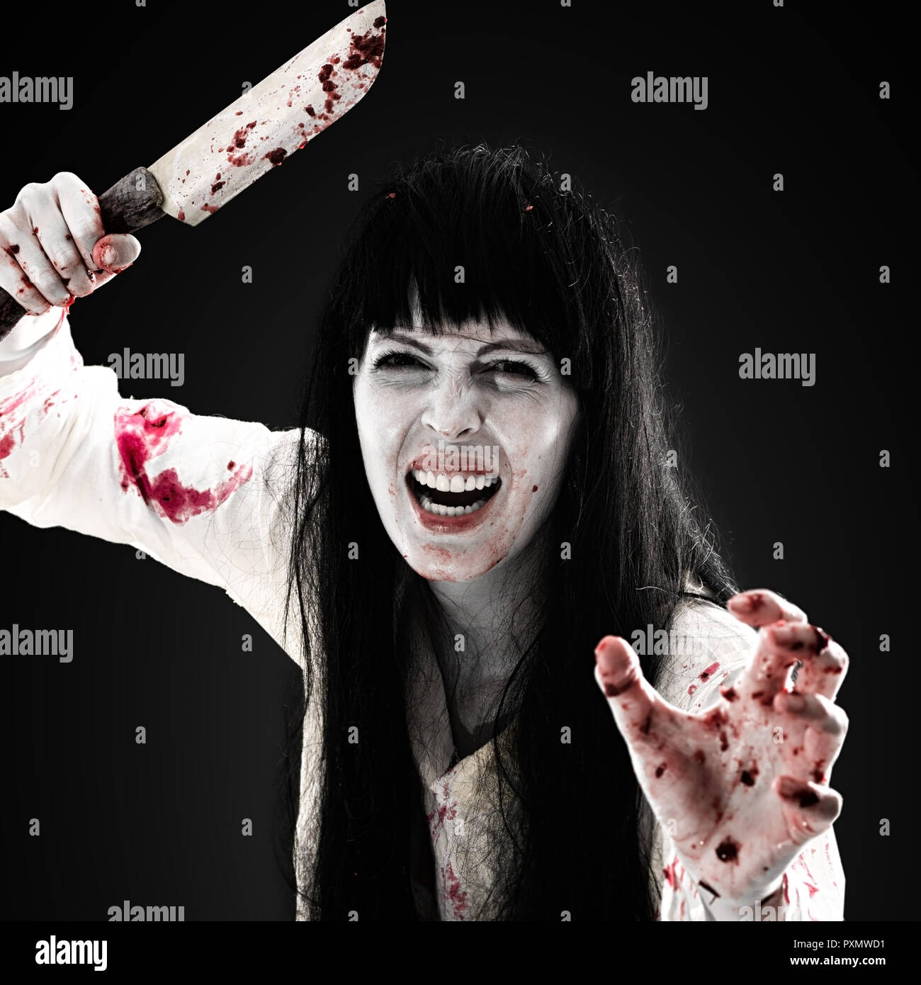 Halloween horror. Crazy sanguinosa scary zombie ragazza con il coltello macellaio cleaver guarda nella fotocamera su sfondo nero Foto Stock
