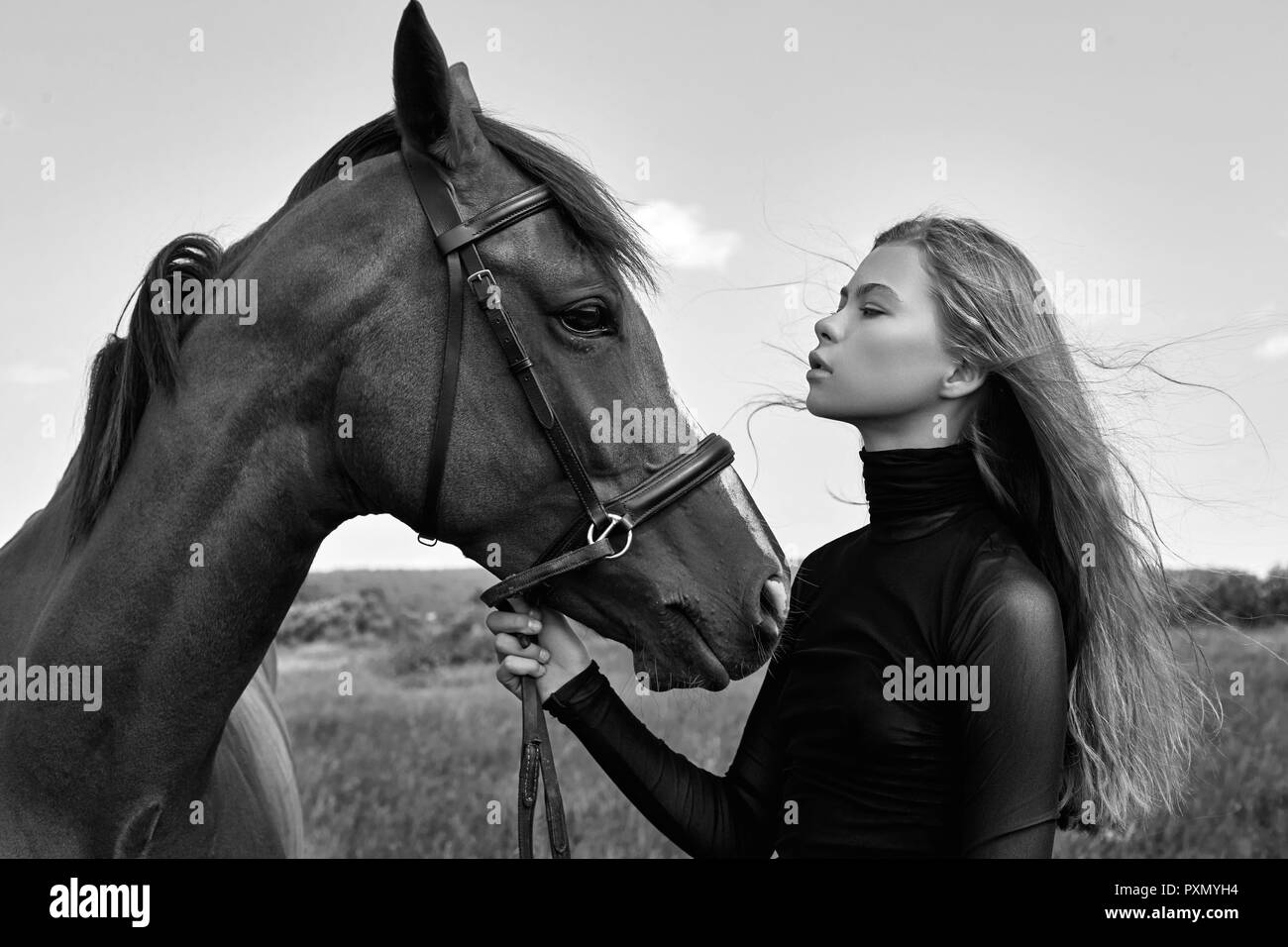 Ragazza rider sorge accanto al cavallo nel campo. Moda ritratto di una  donna e le fattrici sono i cavalli per il villaggio di erba. Donna bionda  holdi Foto stock - Alamy