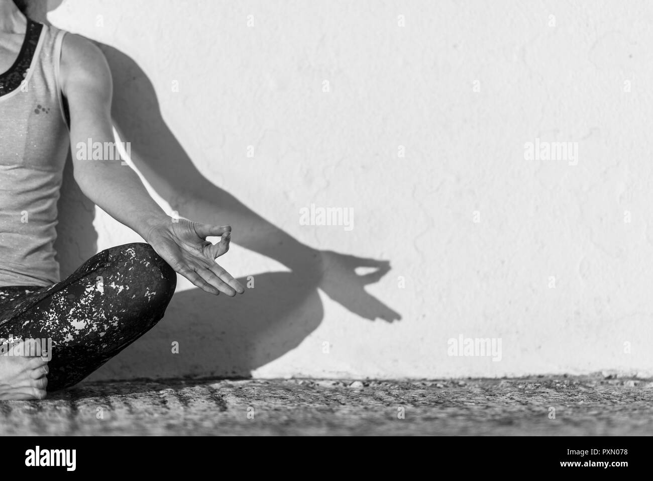 Donna seduta gambe incrociate, meditando, in bianco e nero. Foto Stock