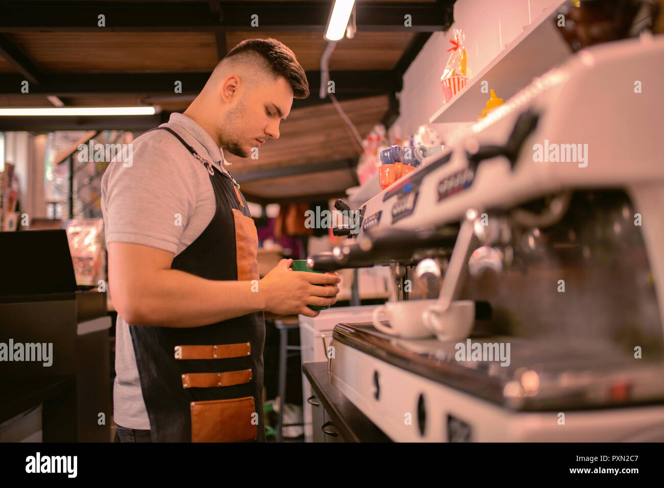 Concentrato giovane barista in piedi vicino alla macchina per il caffè Foto Stock