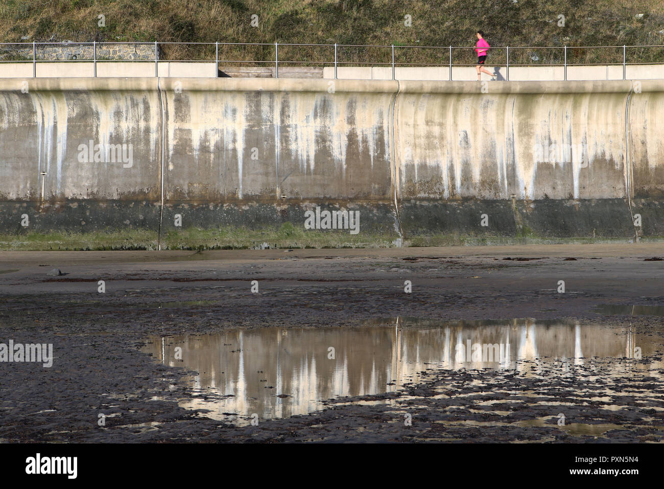 Unico runner in rosa sul calcestruzzo per la difesa del mare la passerella Foto Stock