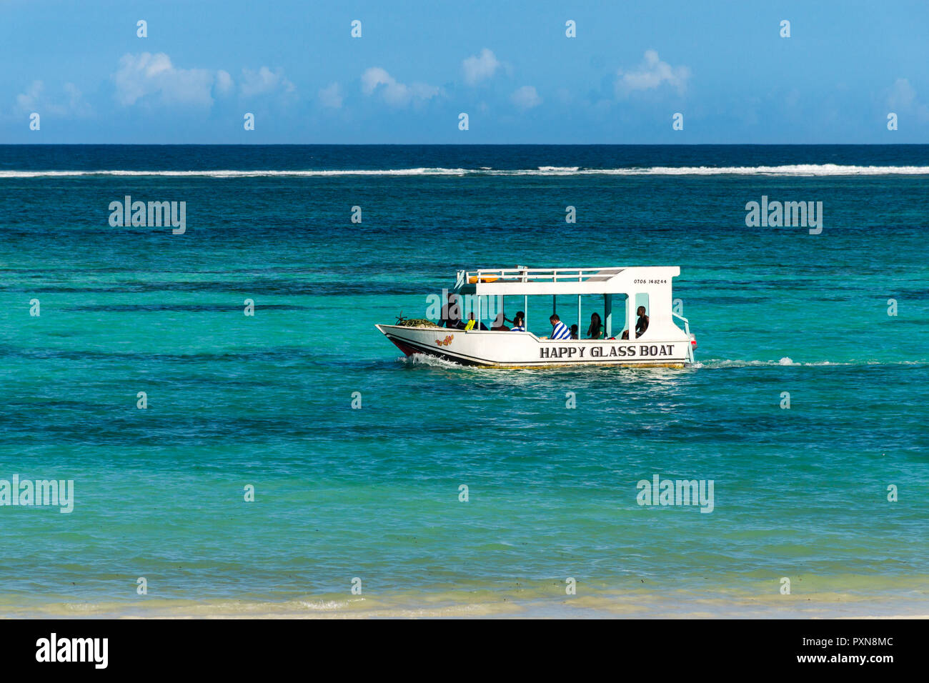 Un legno bianco in barca dal fondo di vetro con vele di turisti lungo la costa dell'Oceano Indiano nella luce del pomeriggio, Diani, Kenya Foto Stock