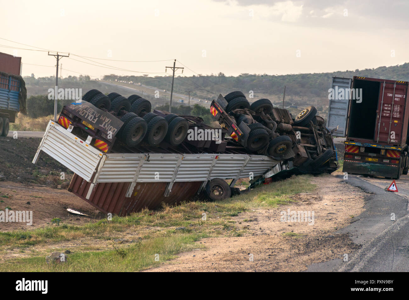 Un autocarro rovesciato dal lato della strada con le ruote in aria, strada di Mombasa, in Kenya Foto Stock