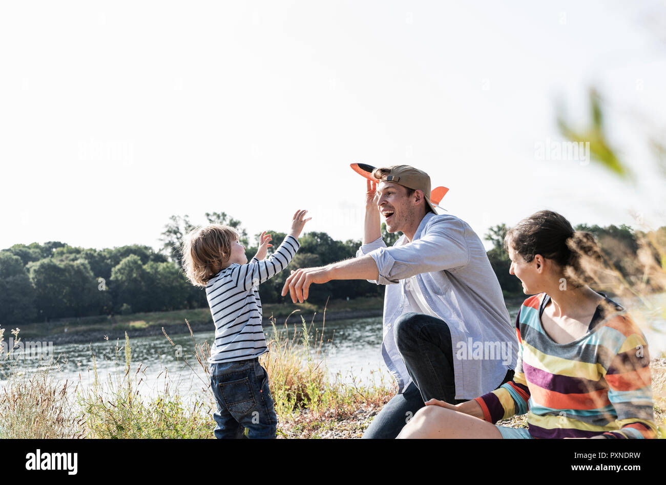 La famiglia felice di relax presso il Riverside, padre e figlio giocare con Toy piano Foto Stock