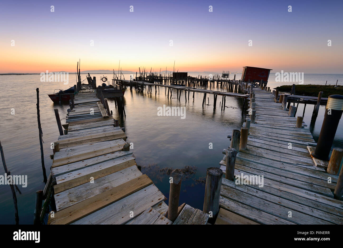 Colonne di legno piers, palafite un porto di pescatori di Carrasqueira al crepuscolo. Alentejo, Portogallo Foto Stock