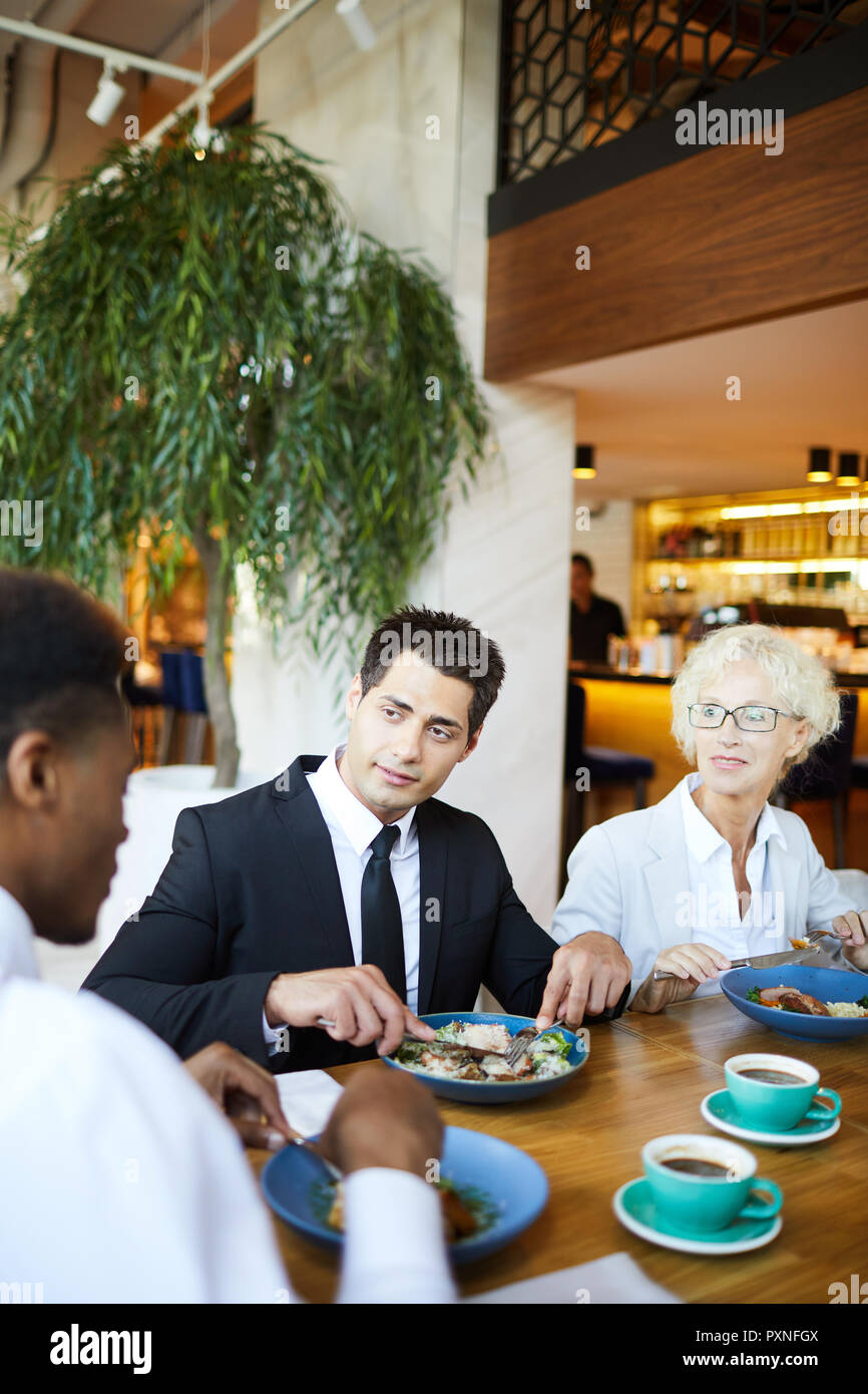 Gruppo di colleghi di lavoro hanno un business talk durante il pranzo al ristorante, essi sedersi e mangiare insalata di verdure e di bere il caffè Foto Stock