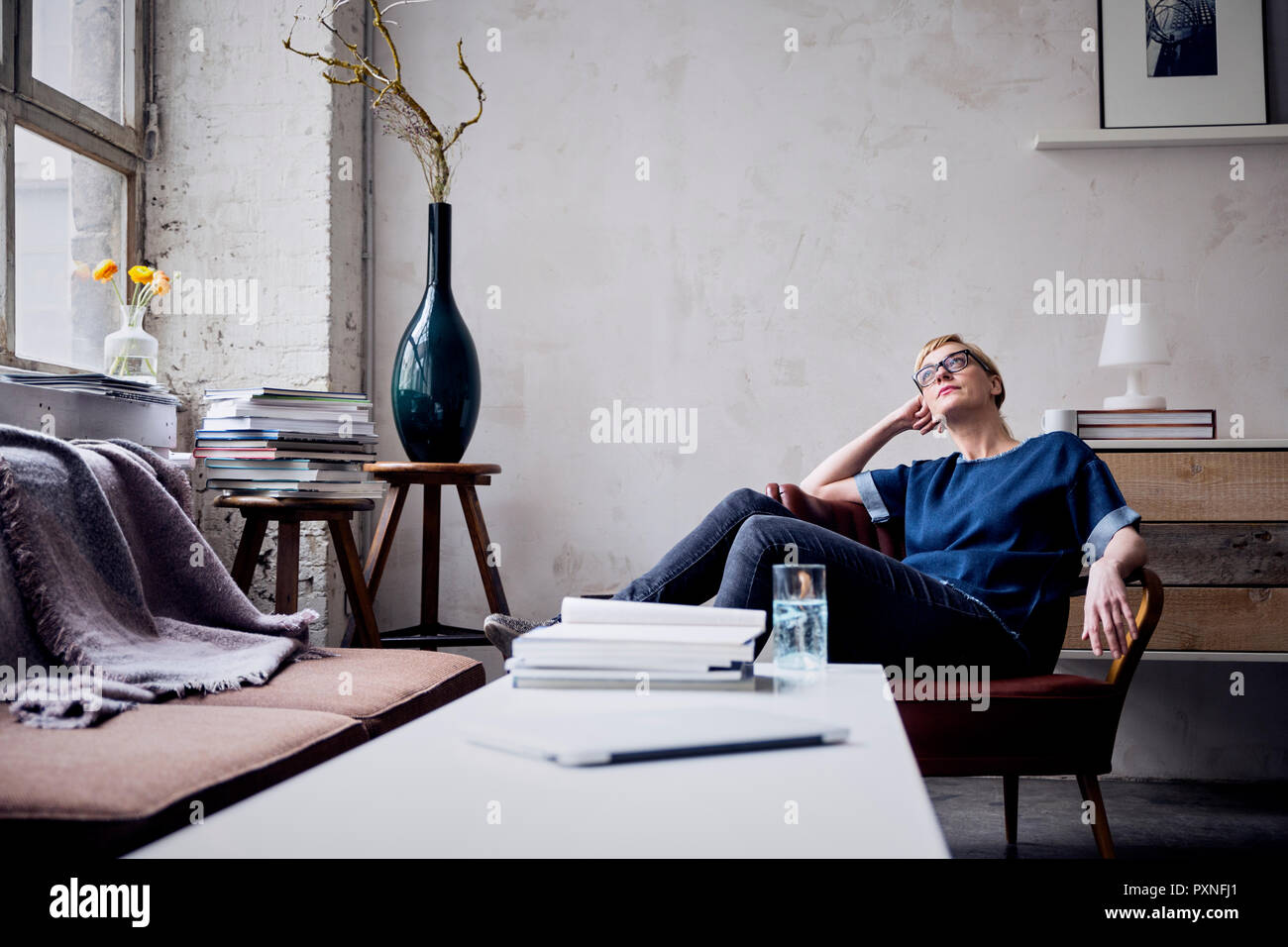 Malinconici donna seduta sulla poltrona loft cercando Foto Stock