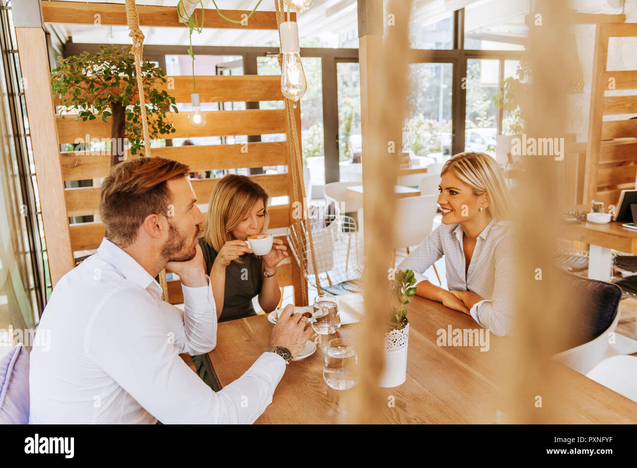 Tre amici riuniti in un cafe Foto Stock