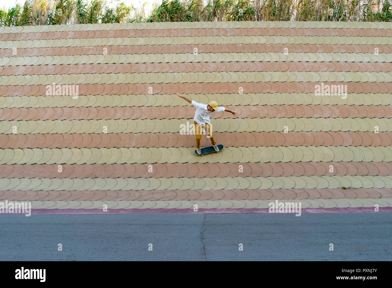 Giovane uomo che cavalca skateboard su una parete Foto Stock