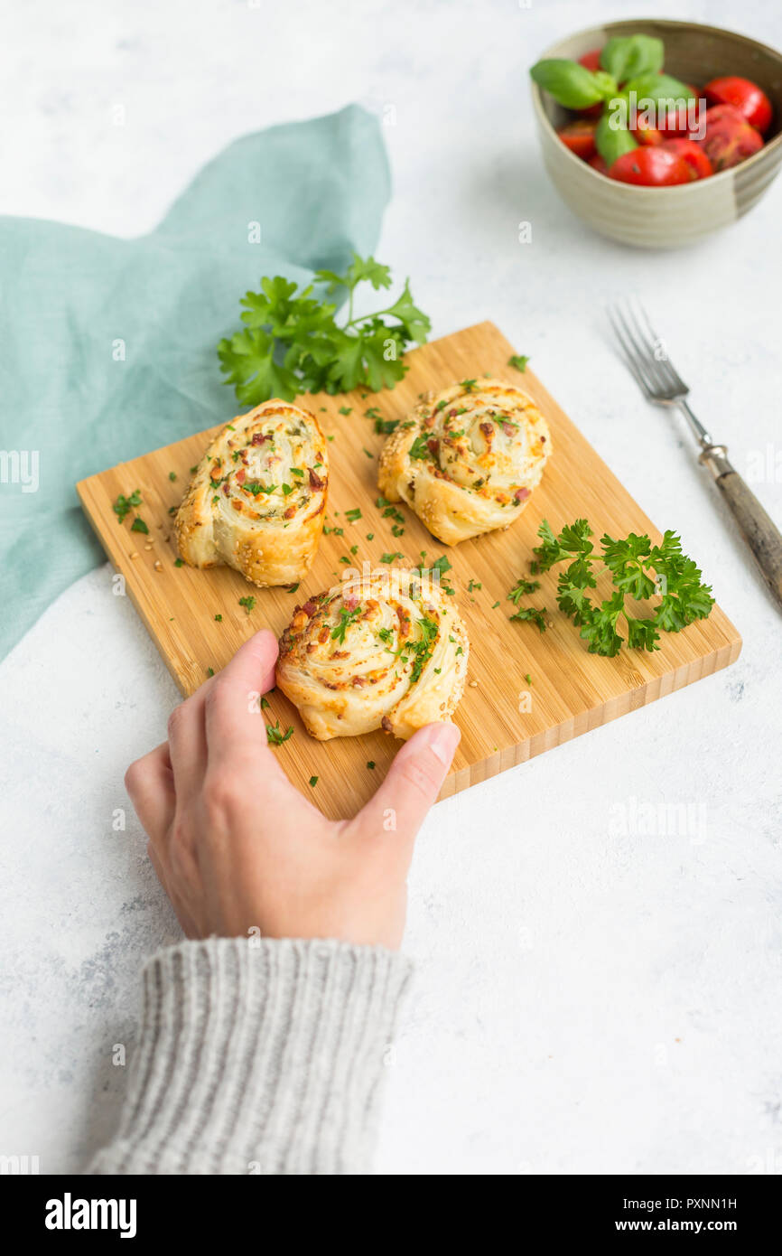 Donna di mano tenendo sticky bun con feta, crema di formaggio, pancetta e prezzemolo Foto Stock
