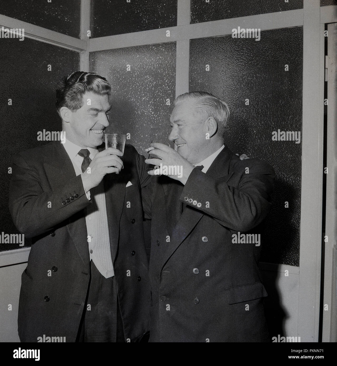 1956, storico, all'interno di un vetro con pannelli in ufficio presso il Millwall FC, il presidente si compiace del club nuovo manager, Ron grigio con un drink e una sigaretta, Millwall Football Club, New Cross, London, SE14, Inghilterra, Regno Unito. Foto Stock