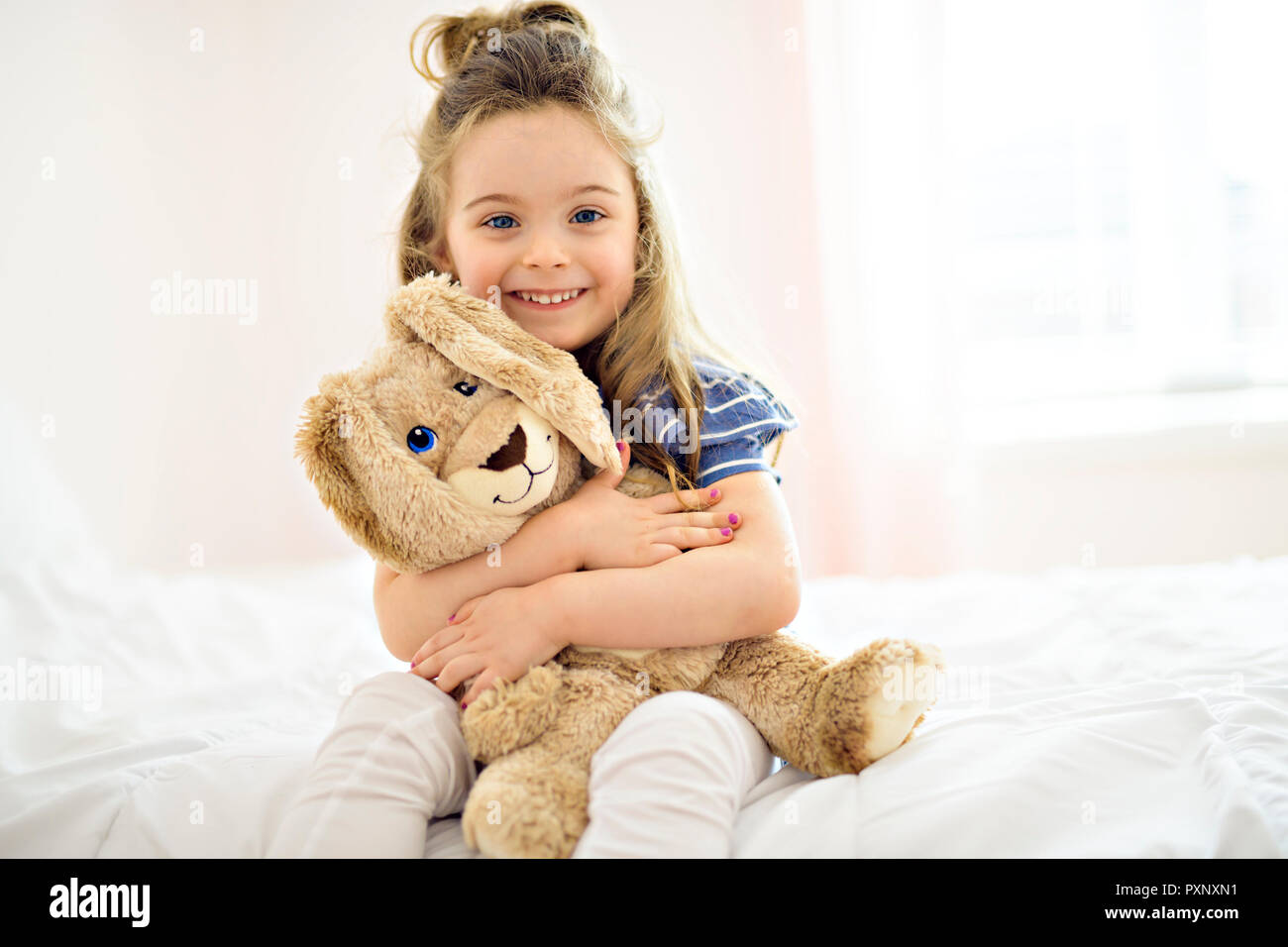Sweet little girl è abbracciando un orsacchiotto sul suo letto a casa Foto Stock