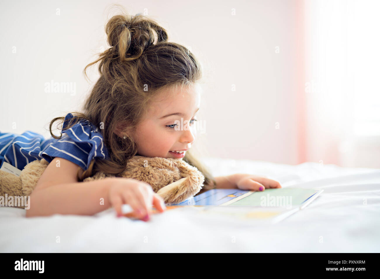 Bambina la lettura di un libro sulla camera da letto Foto Stock