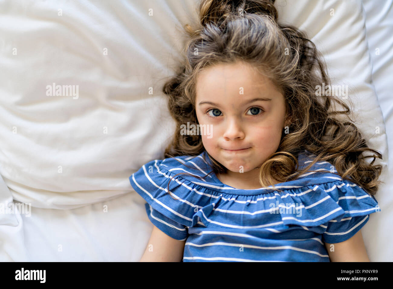 Bambina con la faccia triste giacciono sul letto. Foto Stock
