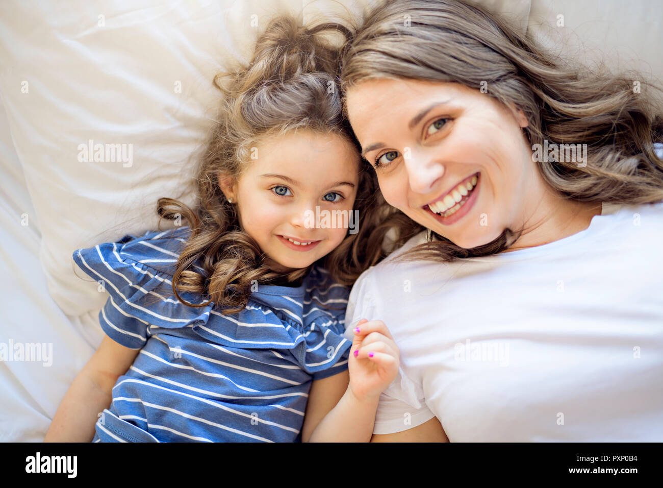 Vista superiore della giovane e bella madre e figlia nel letto di casa Foto Stock