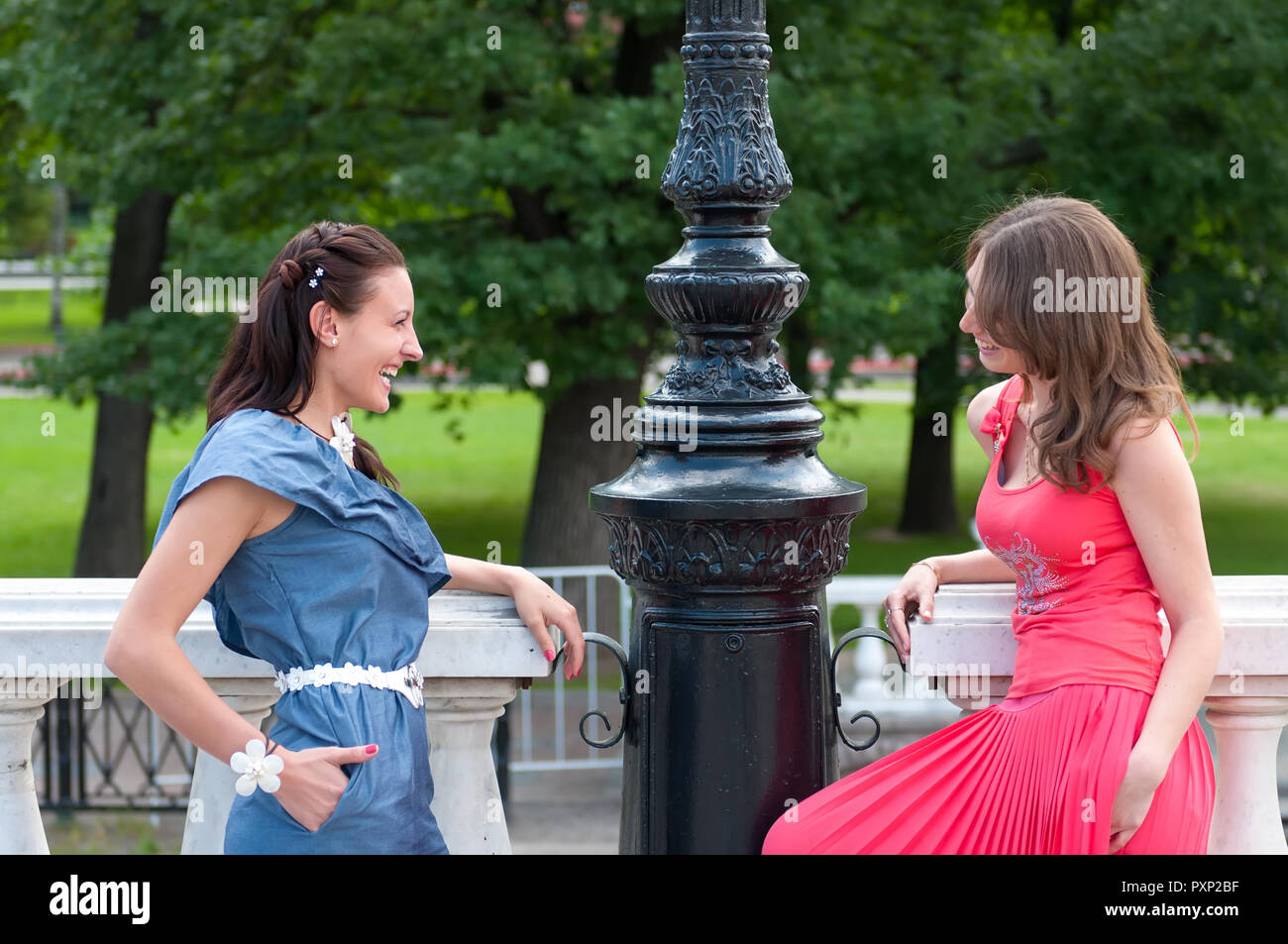 Ritratto di due belle giovani donne in parco e parlare con sorrisi felici. Amici donne attraenti di successo che chiacchierano nel parco Foto Stock