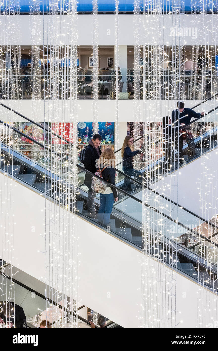 Oxford Street, Londra, Regno Unito. Le luci di Natale appendere sopra le scale mobili nella popolare John Lewis department store Foto Stock