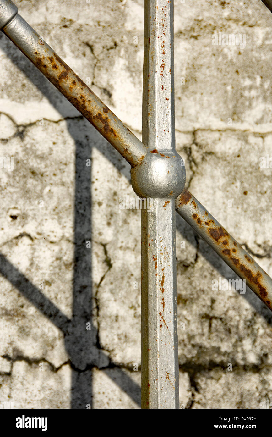 Immagine astratta di argento in posizione verticale e ad angolo della rampa di scale creazione ombra su bianco parete dipinta Foto Stock