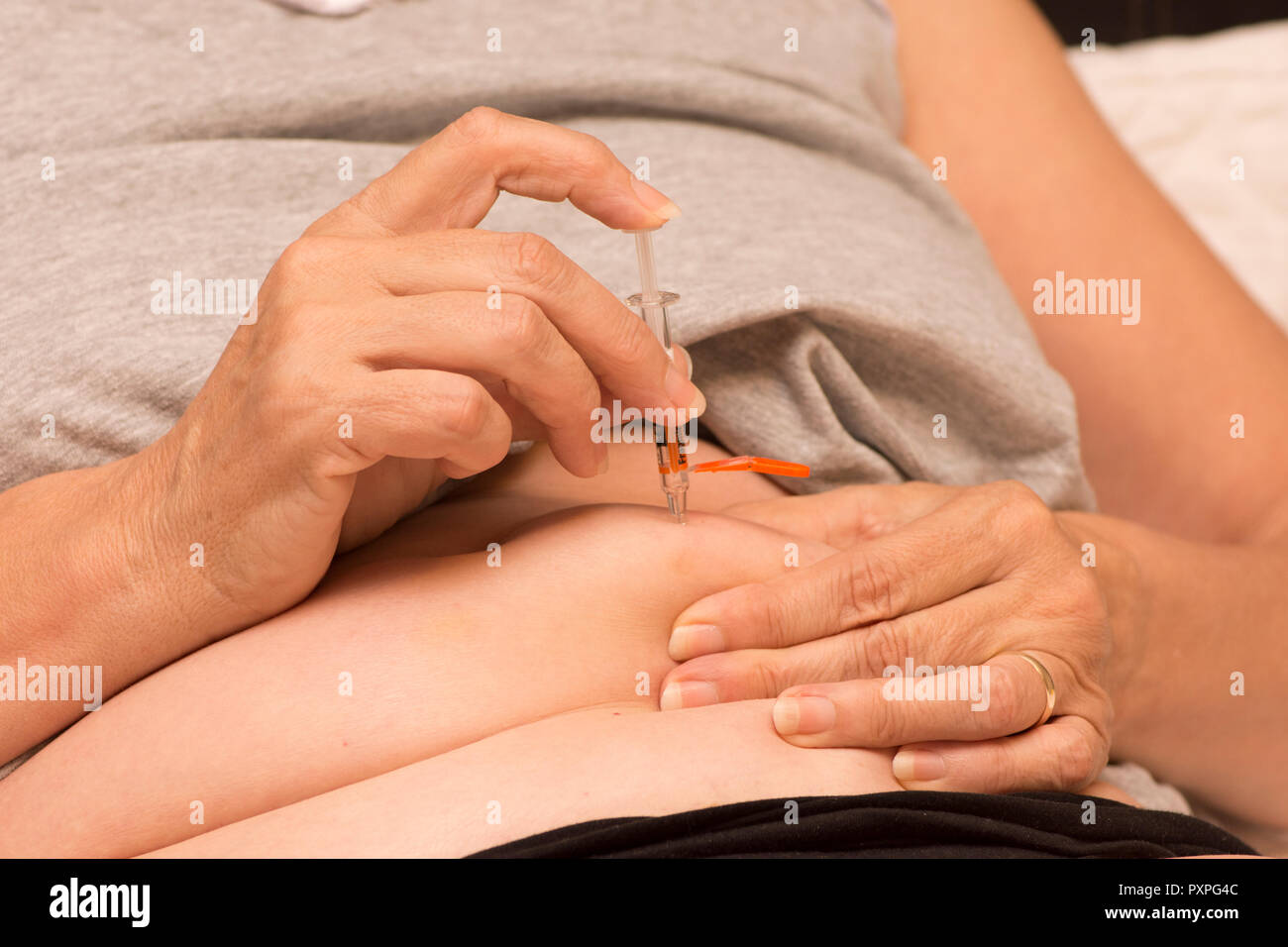 Donna di iniettare il suo pancino con Fragmin, un anti-cagulent per prevenire la formazione di coaguli di sangue dopo un intervento. Foto Stock