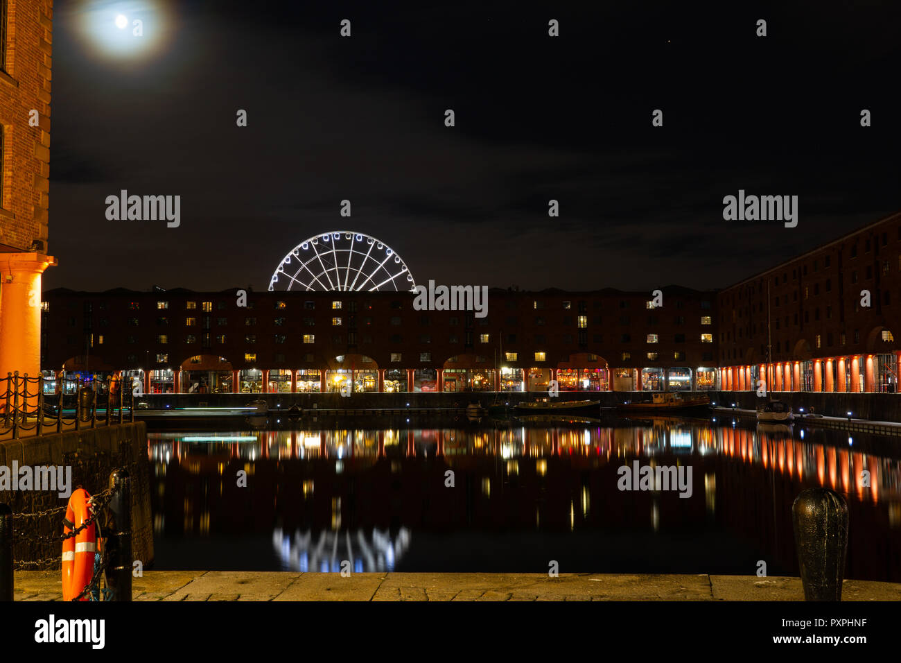 La luna che sorge su Albert Dock, Liverpool, ruota panoramica Ferris in background. Immagine presa in ottobre 2018. Foto Stock