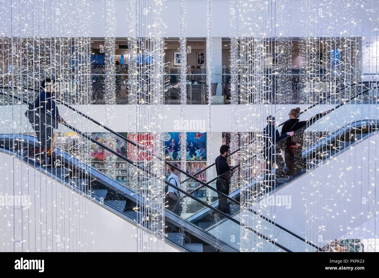 Oxford Street, Londra, Regno Unito. Le luci di Natale appendere sopra le scale mobili nella popolare John Lewis department store Foto Stock