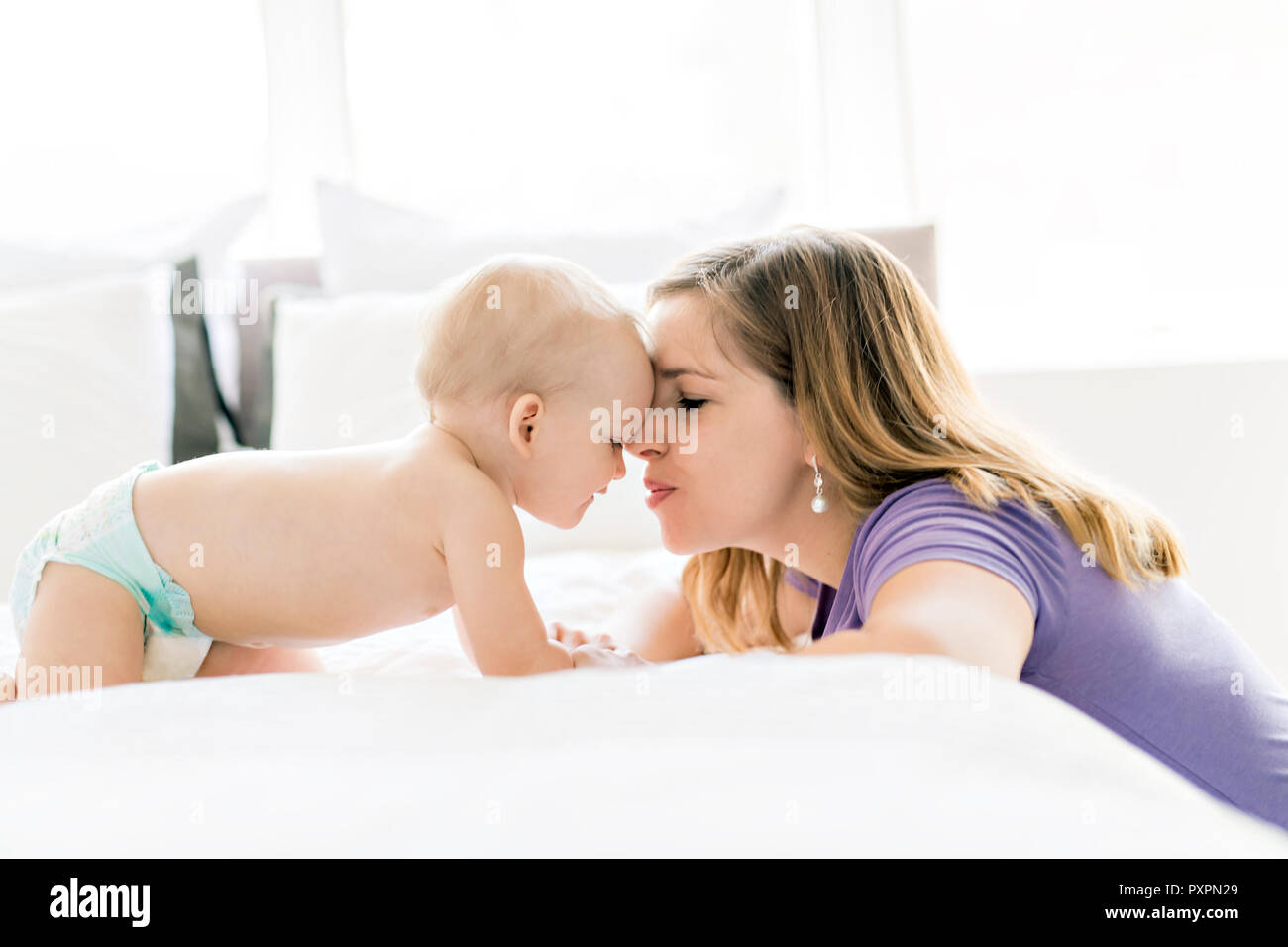 Felice madre con bambino giacente sul letto di casa Foto Stock