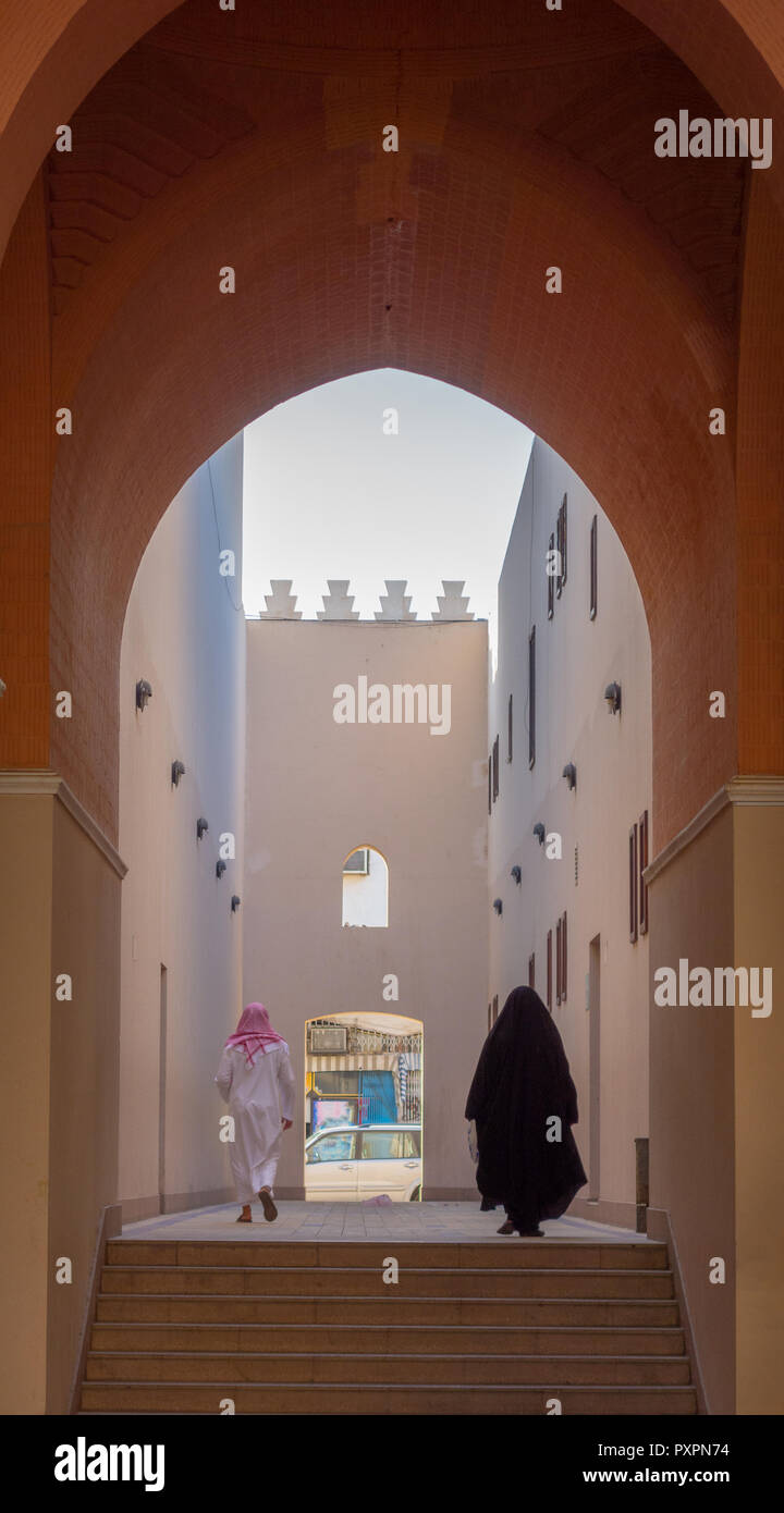 Unidentified l uomo e la donna a piedi verso l'uscita di un arco nella Medina, Arabia Saudita. Foto Stock