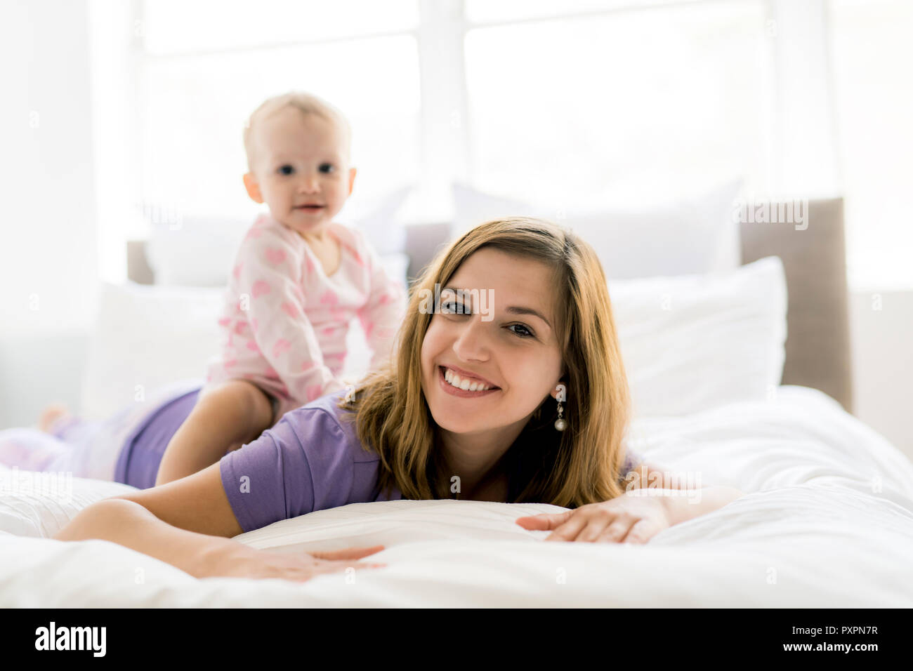 Felice madre con bambino giacente sul letto di casa Foto Stock