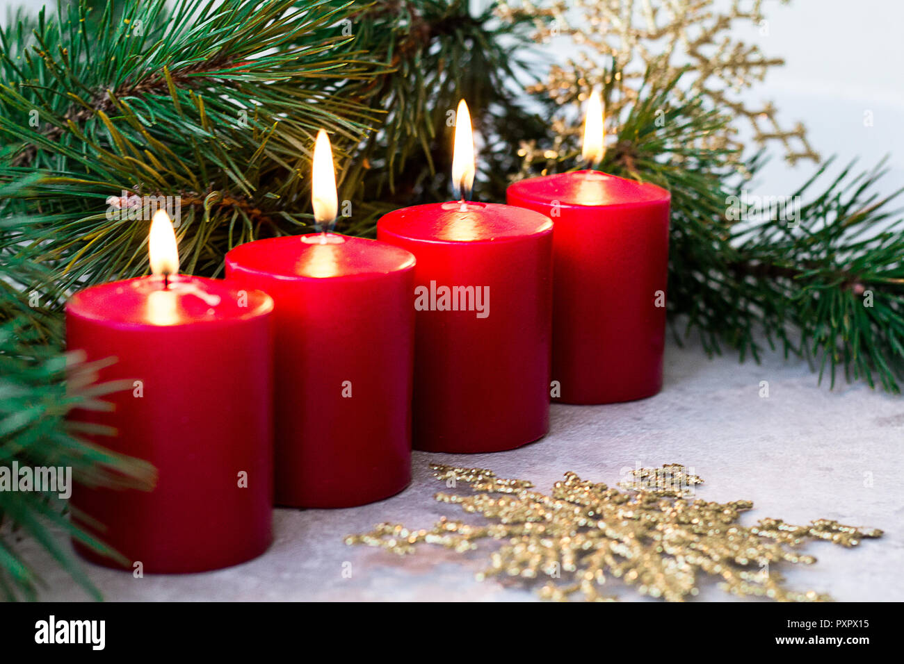 Quattro red burning avvento candele e un ramo di abete su uno sfondo luminoso Foto Stock