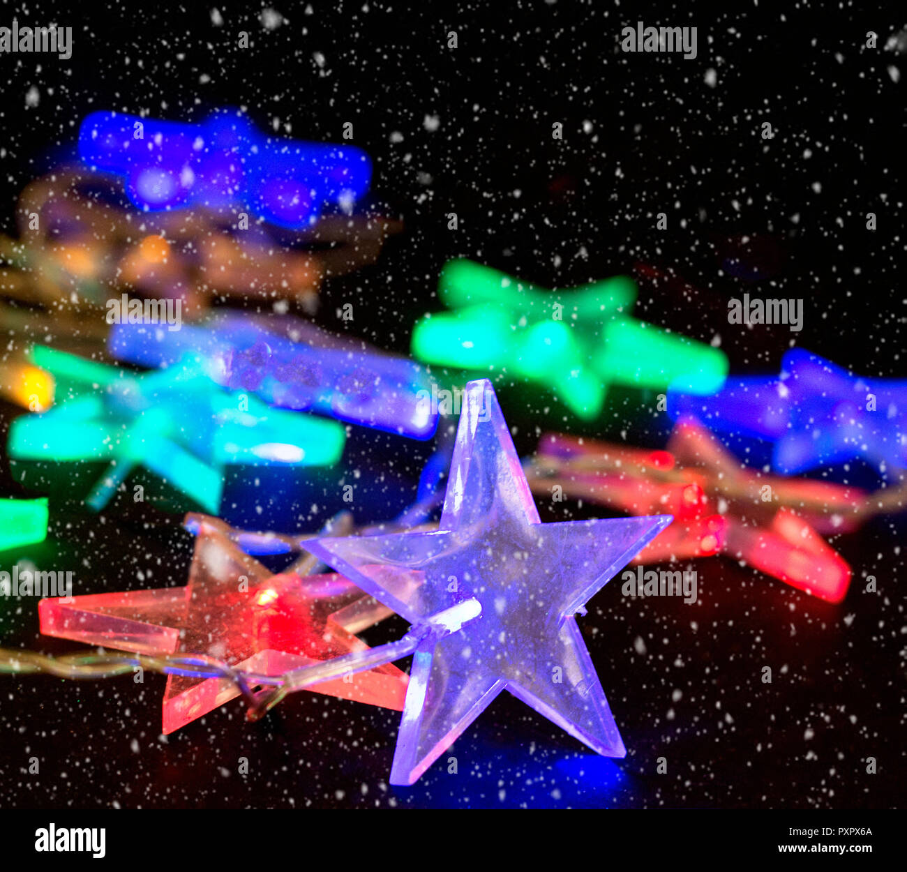 Variopinto incandescente ghirlanda di Natale di stelle su uno sfondo nero Foto Stock