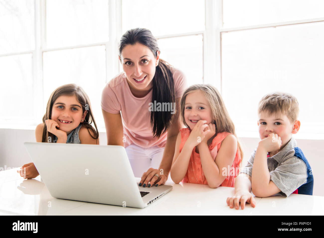 Insegnante con un gruppo di bambini delle scuole con il computer portatile sulla parte anteriore Foto Stock