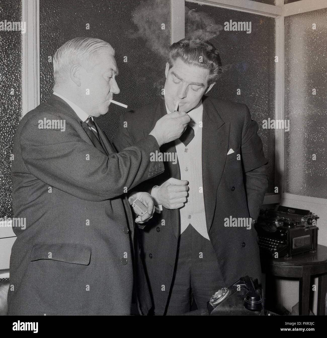 1956, storico in un vetro di finestra di stanza a Millwall FC, il presidente che kis fumatori, accoglie con favore il club di nuovo manager, Ron grigio illuminazione mediante la sua sigaretta, Millwall Football Club, New Cross, London, SE14, Inghilterra, Regno Unito. Foto Stock