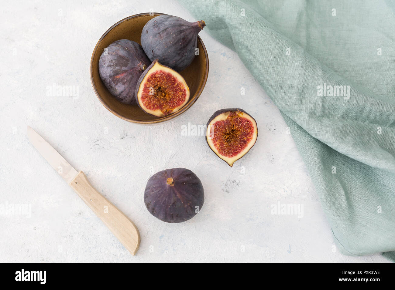Affettato e intera fichi freschi, coltello da cucina e panno per pulizia Foto Stock