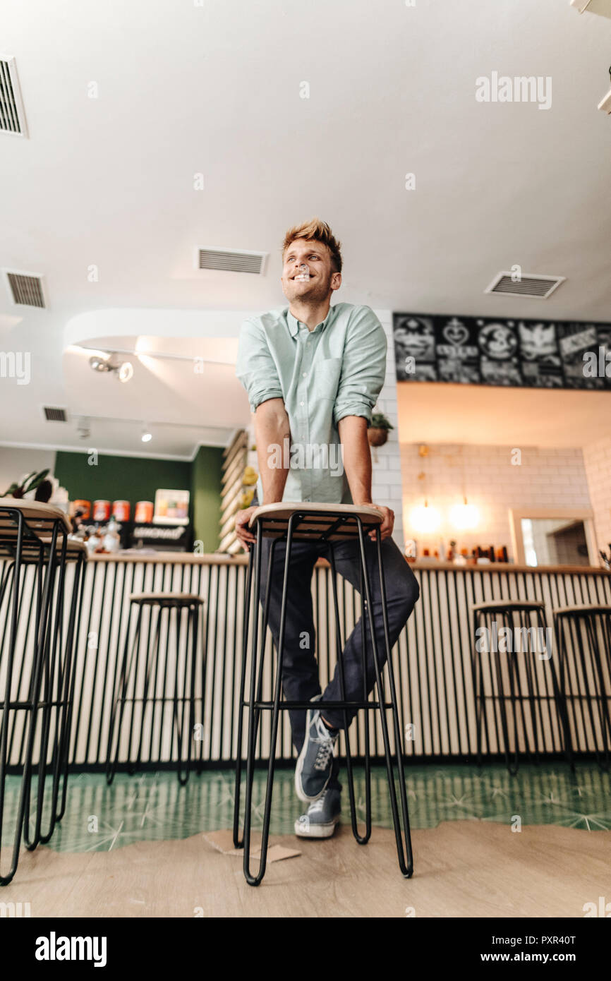 Giovane uomo che lavora nella sua start-up cafe, guardando fiduciosi Foto Stock