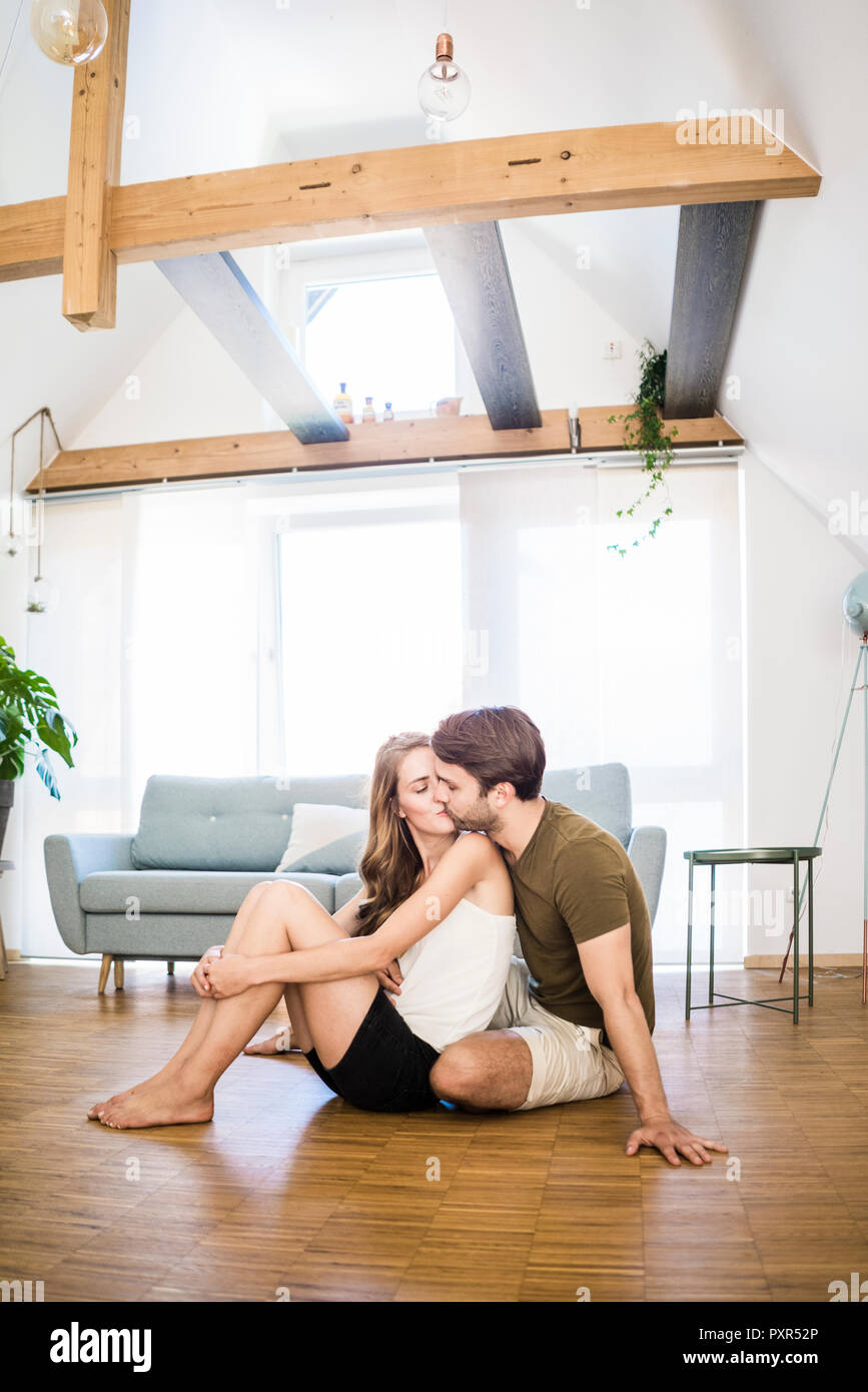 Coppia affettuoso bacio sul pavimento a casa Foto Stock